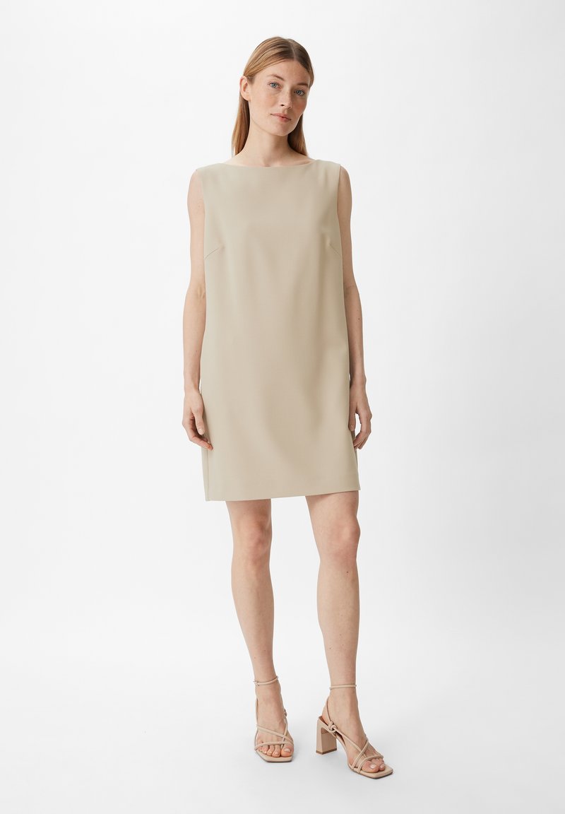 Beiges ärmelloses Shiftkleid mit gerader Silhouette, minimaler Detailgestaltung und glatter Textur. Kombiniert mit beigen Absatzsandalen.