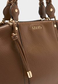 Sac à main en cuir marron avec une finition texturée, doté de poignées supérieures tressées et de garnitures dorées. Logo embossé à l'avant.