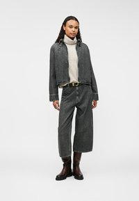 Szara dżinsowa kurtka i szerokie dżinsy w połączeniu z jasnoszarym golfem. Czarny pasek z złotymi elementami i brązowe botki za kostkę.