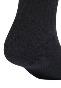 Calcetín negro de algodón con textura acanalada, acabado suave y forma ajustada, con talón reforzado para mayor durabilidad.