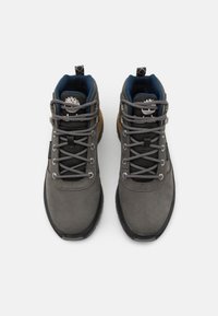 Szare buty do wędrówek z górną częścią z gładkiej zamszowej skóry, czarną gumową podeszwą oraz wzorzystymi szarymi sznurówkami. Posiadają ciemnoniebieską podszewkę i uchwyt z tyłu.