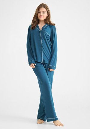 Conjunto de pijama color azul verdoso con mangas largas y pantalones, que presenta un ribete blanco en el cuello, los puños y los bolsillos. Tejido suave con un corte holgado.