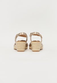 Brown metallic sandals with ankle straps, woven esparto wedge heels, and flat rubber soles, showing back view and minimalist design.