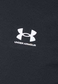 Crni sportski majica izrađena od glatke, rastezljive tkanine s istaknutim bijelim Under Armour logom na prednjoj strani.