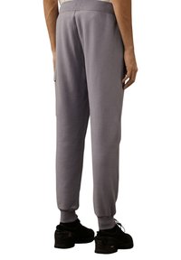 Graue Jogginghosen mit elastischem Bund und Bündchen, ausgestattet mit einer Seitentasche. Hergestellt aus weichem Stoff mit glatter Textur und passgenauer Passform.