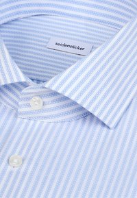 Chemise à rayures bleu clair et blanches à boutons avec un col classique, dotée d'une étiquette portant la mention "seidensticker" et d'une texture de tissu lisse.