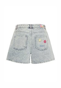 Shorts en denim bleu clair à taille haute, deux poches arrière, avec des broderies de soleil, coquillage et vagues sur la poche droite.