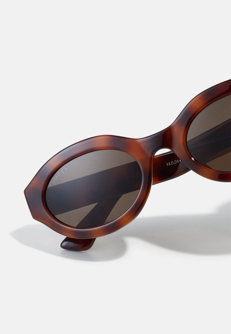 Braune Schildpatt-Sonnenbrille mit einem runden, achteckigen Rahmen und dunklen Gläsern; verfügt über ein kleines Akzentdetail am Bügel.