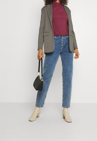 Šedý kostkovaný blazer, burgundský svetr, vysoké modré džíny, krémové kotníkové boty a malá černá kabelka.