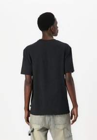 Sort bomulds t-shirt med korte ærmer og rund halsudskæring, med en lige kant og minimalistisk design. Ingen synlige grafikker eller mønstre.