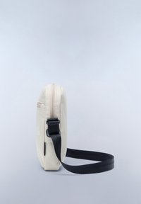Canvas crossbody bag in off-white with a zip closure, black strap, and textured surface. Features a side pocket and minimal branding.