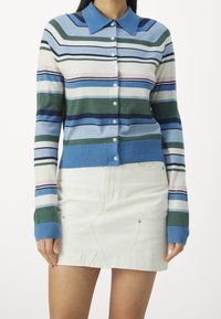 Randig stickad cardigan i nyanser av blått, grönt, rosa och crème, med knäppning fram och krage. Lämplig för lager-på-lager-stil.