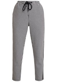 Kalhoty s černo-bílým kostkovaným vzorem houndstooth, elastickým pasem, šňůrkou na stažení a černými bočními pruhy. Úzký přiléhavý střih.