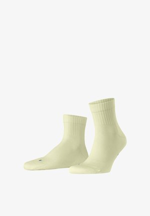 Zwei hellgelbe Socken bis zur Mitte der Wade mit geripptem Bündchen vor weißem Hintergrund.