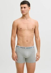 Harmaat boxerit, joissa on pehmeä tekstuuri ja sinivalkoinen brändätty vyötärönauha. Muotoilu on yksinkertainen ja istuva.