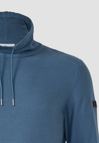 Maglione blu lavorato a maglia con collo alto, dettaglio a coste sulle spalle, coulisse con punte in metallo e piccolo patch logo nero sulla manica.