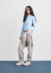 Ανοιχτό μπλε ριγέ μπλουζάκι μακρύ μανίκι συνδυασμένο με γκρίζα φόρμα, και ροζ φούτερ δεμένο στη μέση. Ανοιχτόχρωμα, με επένδυση αθλητικά παπούτσια.