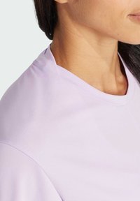 Fialová tričko s okrúhlym výstrihom a krátkymi rukávmi, vyrobené z jemnej, hladkej látky. Viditeľné švy na ramene.