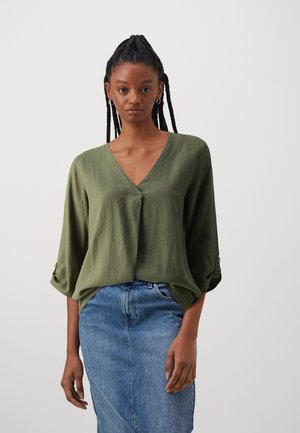 Camicia leggera in misto lino di colore verde oliva, con scollatura a V e maniche a tre quarti, dotata di polsini arrotolati e vestibilità comoda.