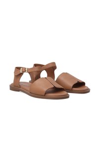 Bruine leren sandalen met uitsnijdingen, enkelband en gesp-sluiting. Platte zool met minimalistische stijl enopen teen.