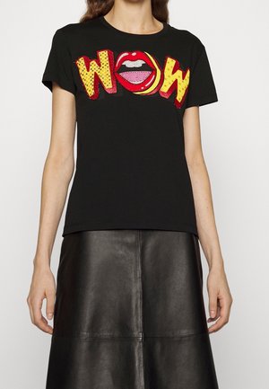 Frau trägt schwarzes T-Shirt mit roten Lippen und gelbem Comic-Stil "WOW" Text über schwarzem Lederrock.