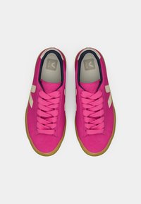 Pink athletic shoes with a textured fabric upper, contrasting beige accents, rubber sole, and flat laces. Rounded toe and low-profile design.