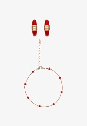 Guldarmbånd med små røde perler og matchende røde og gyldne øreringe i runde hoops på hvid baggrund.