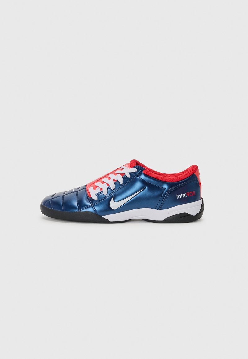 Chaussure de football basse Nike Total 90 III bleue et rouge avec lacets blancs, logo Swoosh blanc et semelle extérieure noire, vue de profil.