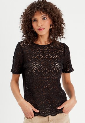 Top de encaje negro de manga corta con un dobladillo festoneado y patrones florales intrincados, con una silueta ajustada y una textura ligeramente transparente.