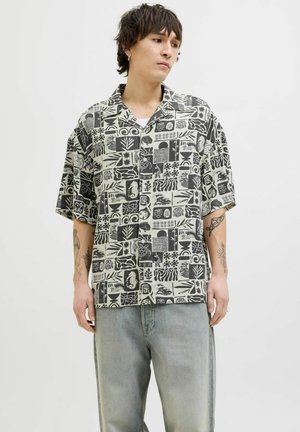 Short-sleeved button-up shirt in light beige with black abstract patterns and designs; relaxed fit; made from a smooth fabric.