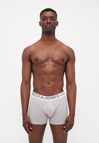 Graue Boxershorts mit einem weißen Gummibund, der "JACK & JONES" in Schwarz trägt. Glatte Textur und figurbetontes Design.