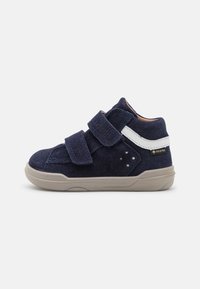 Scarpa alta in suede blu navy con due cinturini in velcro, una striscia di accento bianca e una suola in gomma beige con dettagli perforati.