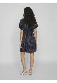 Mekko, jossa on valkoiset pystysuorat raidat, lyhyet hihat ja joustava vyötärö. Yhdistetty vaaleanvärisiin avokkaisiin.