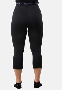 Black capri leggings made of stretchy fabric with a high waistband featuring the brand name "SWOUNT." Smooth texture, form-fitting design.