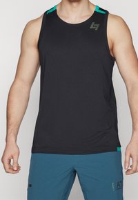 Camiseta atlética sin mangas negra, hecha de tela texturizada, con acentos verdes en los hombros y detalle del logo en el pecho.