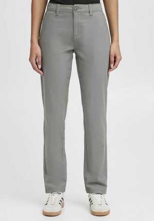 Grey pants made of smooth fabric, featuring a straight cut, front pockets, and a button closure. Paired with white sneakers.