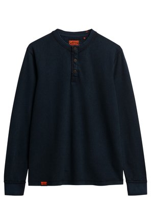 Donker marineblauwe long sleeve henley shirt met een gestructureerde afwerking, drie knopen bij de hals en een logo patch op de zoom. Klassieke pasvorm met ribgebreide manchetten.