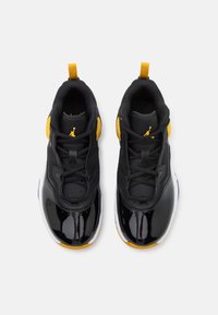 Černé a žluté sportovní boty s lesklým lakovaným špičkou, síťovaným svrškem a tkaničkami, s poutkem na patě a logem.