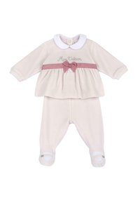 Krémový dětský outfit obsahující dlouhý rukáv top s bílým límcem, růžovými mašličkami a odpovídajícími kalhotami se špičkami.
