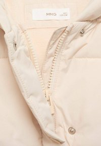 Veste en duvet beige clair avec une fermeture éclair à l'avant, des fermetures à pression et une doublure douce. Comprend une étiquette indiquant la taille et la marque.