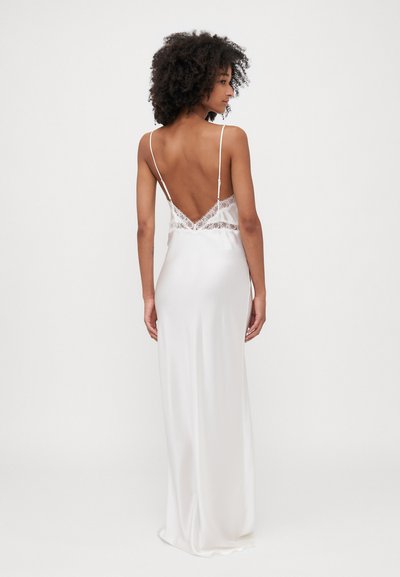 Weißes Satin-Kleid mit tiefem V-Ausschnitt hinten, zarten Spitzenverzierungen, dünnen verstellbaren Trägern und glatter Oberfläche. Schlanke und eng anliegende Silhouette.