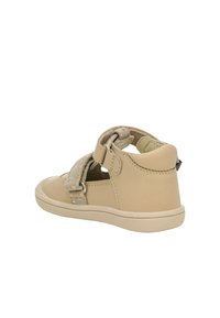 Beige Leder-Sandale mit einem strukturierten, gemusterten Riemen und Klettverschluss. Abgerundete Spitze, flexible Sohle und minimale Nähdetails.