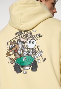Yellow hoodie featuring a graphic on the back depicting a cartoon dog and golf ball in a green golf cart, surrounded by golf clubs and balls.
