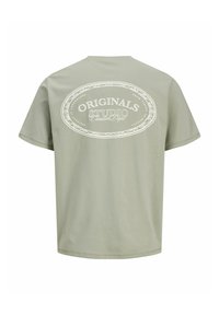 Müntroheline lühikeste varrukatega T-särk, mille tagaküljel on suur valge ovaalne graafika koos tekstiga, valmistatud pehmest puuvillast kangast.