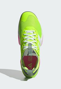 Neon groene sportschoen met een gestructureerde bovenkant, witte veters, roze accenten en een grijze trekband aan de achterkant. Beschikt over een gevoerde zool.
