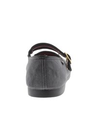 Zapato plano de ante negro con puntera redondeada, tira elástica en el talón y detalle en dorado en la tira. Textura suave, diseño de bajo perfil.