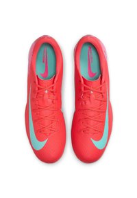 Pantofi de fotbal roșii aprinși cu un finisaj texturat, dotati cu un Swoosh mare de culoare albastru deschis și o talpă interioară turcoaz. Șireturile sunt legate neat.
