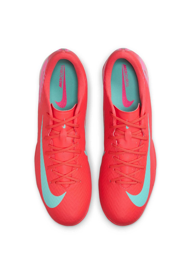 Jasnoczerwone buty piłkarskie o teksturowanym wykończeniu, z dużym, jasnoniebieskim logo Swoosh i turkusową wkładką. Sznurowadła są starannie związane.