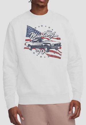 Mann trägt weißen Pullover mit Vintage-Ford-Mustang-Auto und amerikanischer Flagge, Vintage-Text "Mustang 70".