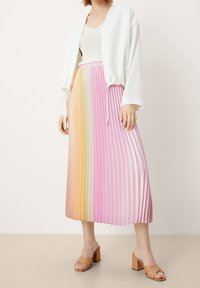 Gonna midi plissettata in tonalità sfumate di rosa e arancione, abbinata a una giacca bianca corta e sandali tan con tacco a blocco. Texture liscia.